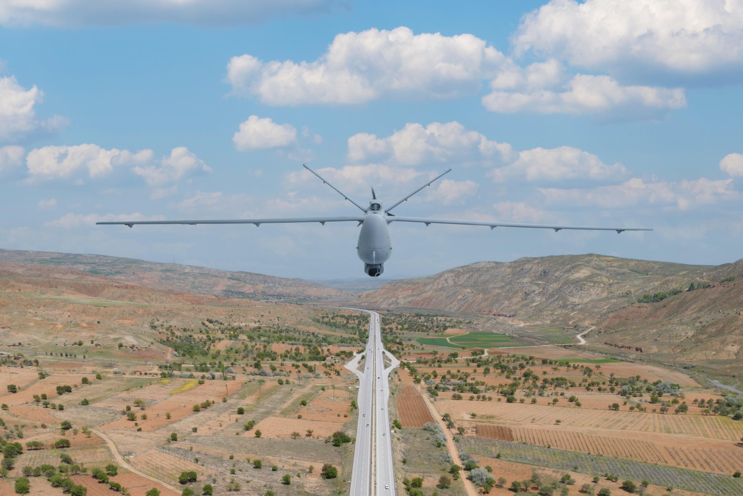 Airplane taking off from runway, flying above fields and hills with clear skies.